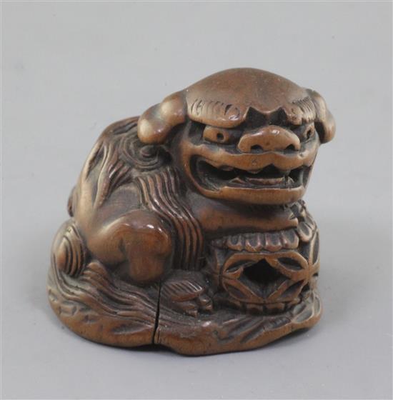 A Japanese wood netsuke of a shishi, seated on a rock, 19th century, w. 3.6cm
